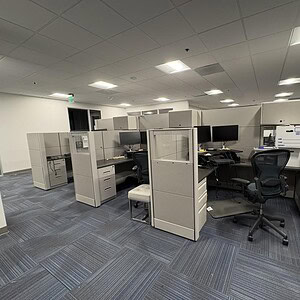 Office cubicles with privacy panels and ergonomic chairs in a modern workspace.