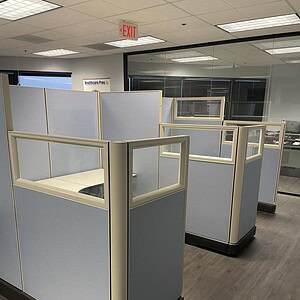 Office cubicles with beige and blue panels for workspace privacy.