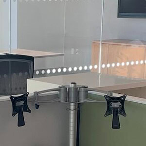 Knoll dual silver monitor arms mounted on a desk for ergonomic workspace setup.