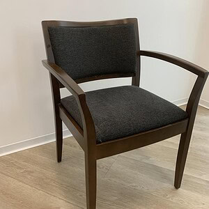 Elegant wooden armchair with dark fabric upholstery, showcasing modern design and craftsmanship.