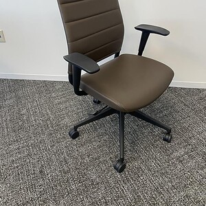 Ergonomic high back brown office chair with adjustable armrests and wheels.