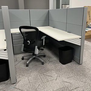 Herman Miller grey and white office cubicle with ergonomic chair and workspace setup.