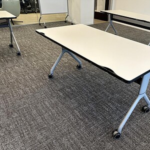 Nesting tables with white surfaces and black edges, ideal for versatile office or conference room se.