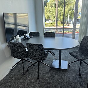 Modern Knoll grey bullet top table with black patterned chairs in a bright office space.