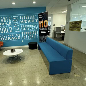 Blue office sofa bench in a corporate lobby with motivational wall art.