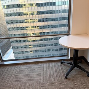 Corner table with white top and black base in an office setting.