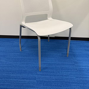 White stack chair with perforated backrest, ideal for contemporary office or lounge environments.