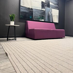 Modern purple sofa with abstract wall art in contemporary office setting.