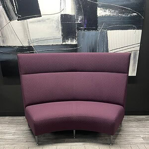 Modern purple curved couch with high backrest and sleek design.