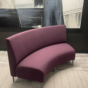 Krug purple short curved couch with sleek design and plush upholstery.