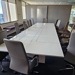Allsteel white glass conference table, 18x5 feet, with powered outlets, in a modern office setting.