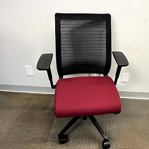 Quality Steelcase Think office chair with black mesh back and red cushioned seat for ergonomic comfo.