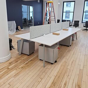 Benching desks with colorful dividers in modern office setting.