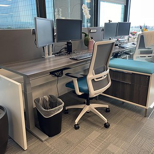 Modern office workstation with multiple monitors and ergonomic chair in a bright workspace.