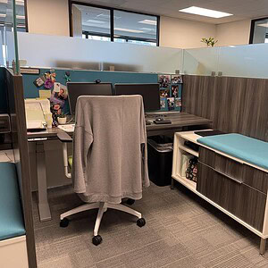 Office cubicle with desk, chair, and storage unit in modern workspace.