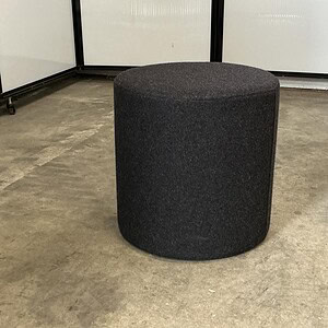 Black round ottoman for versatile seating and decor.