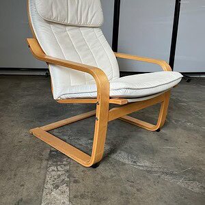 Sleek white lounge chair with wooden sled base, perfect for modern living spaces and relaxation.