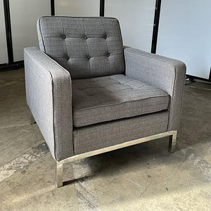 Grey tufted fabric lounge chair with chrome base for modern living spaces.