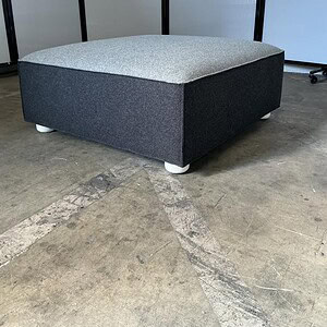 Ottoman with two-tone grey upholstery, perfect for modern living spaces.