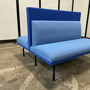 Contemporary blue lounge seat with high backrest and sleek black legs.