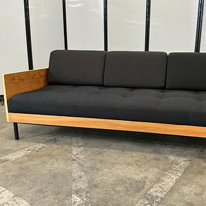 Black upholstered sofa with natural wood veneer frame, 78-inch width, modern design.