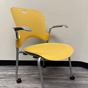 Yellow Herman Miller Caper chair with armrests and casters.