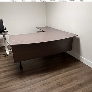 Shaped electric desk in Slate Grey finish with modesty panel for office comfort and style.
