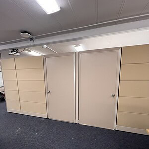 Office cubicle walls with doors in neutral tones.