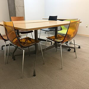 Herman Miller Eames conference table with six amber chairs in modern office setting.