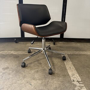 Herman Miller Eames-inspired black leather office chair with wood veneer and chrome base on casters.