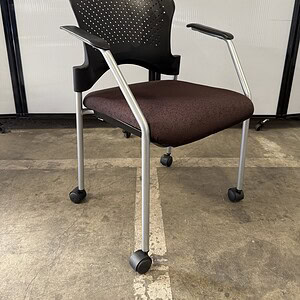 Office chair with black mesh backrest and mocha fabric seat on casters.