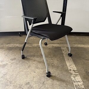 Office chair with black perforated back and casters for mobility.