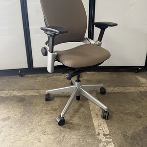 Ergonomic office chair with neutral fabric, adjustable armrests, and silver frame.