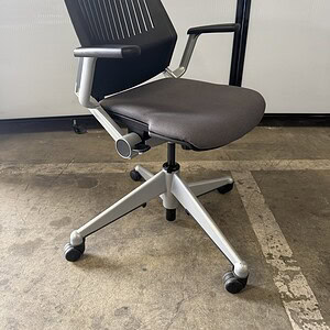 Ergonomic office chair with black perforated back and grey fabric seat.