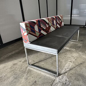 Bench with patterned backrest and sleek chrome legs for modern outdoor or indoor seating.