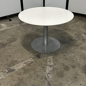 Round conference table with white top and sleek silver base, ideal for modern office spaces.
