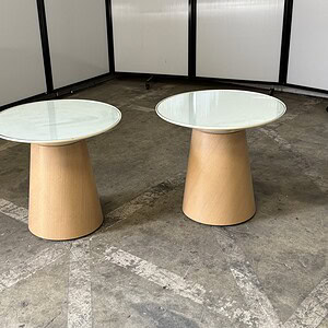 Modern round glass tables with wooden bases, ideal for office or lounge settings.