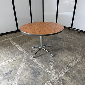 Round wood laminate table with chrome base, ideal for office or conference room settings.