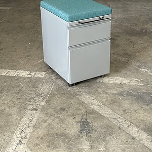 Herman Miller mobile pedestal with aqua green cushion and orange accents.