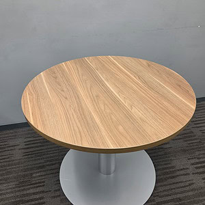 Round walnut top conference table with steel cylinder base for modern office spaces.