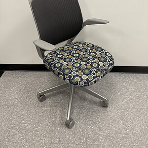 Office chair with black mesh backrest and patterned cushioned seat, ergonomic design for comfort and.