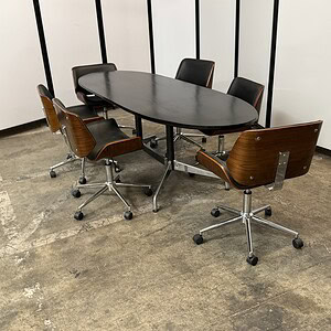 Herman Miller Eames conference table with six chairs in modern office setting.