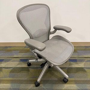 Aeron Size B ergonomic office chair in silver with mesh back and adjustable armrests.