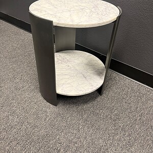 Round marble top end table with black metal base, modern design, perfect for living room or bedroom.