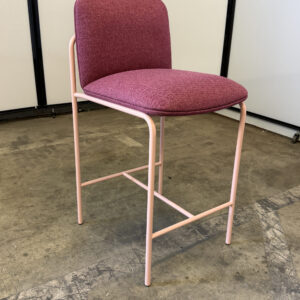 Bar stool with maroon upholstered seat and backrest, pink metal frame, ideal for modern bar areas.