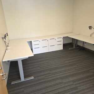 Height adjustable L-shaped office desk with credenza and pedestals for ergonomic workspace.