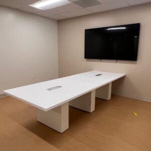 Conference room table with integrated power outlets and large wall-mounted TV.