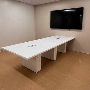 Conference room table with integrated power outlets and a large flat-screen TV.