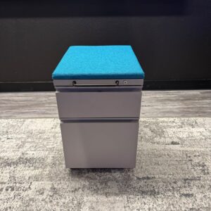 Modern gray storage ottoman with blue cushioned top for versatile use.