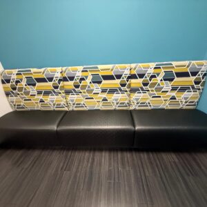 Modern office waiting area with colorful geometric patterned bench and vibrant blue wall.